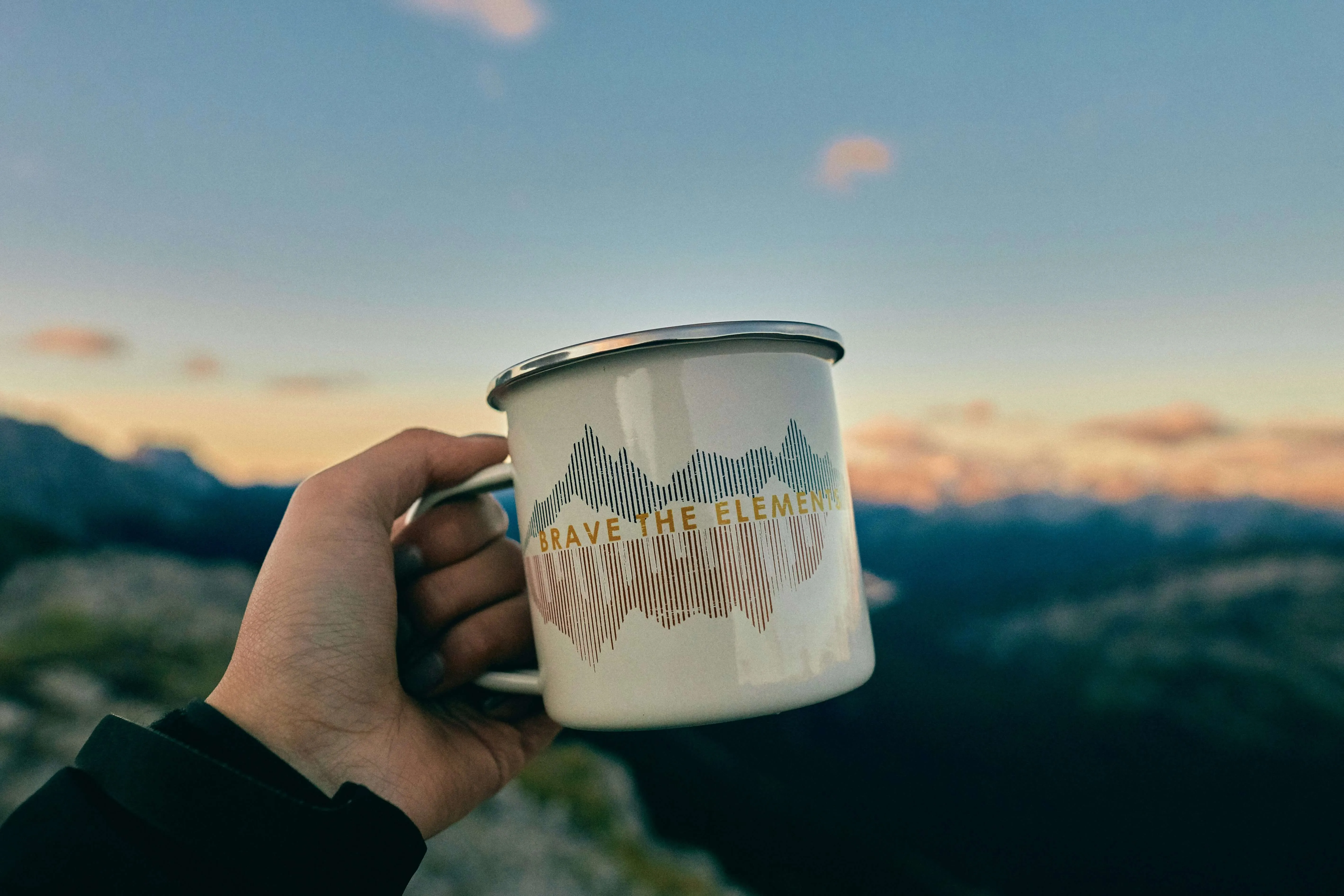 An insulated camping mug full of hot coffee on a wooden table.