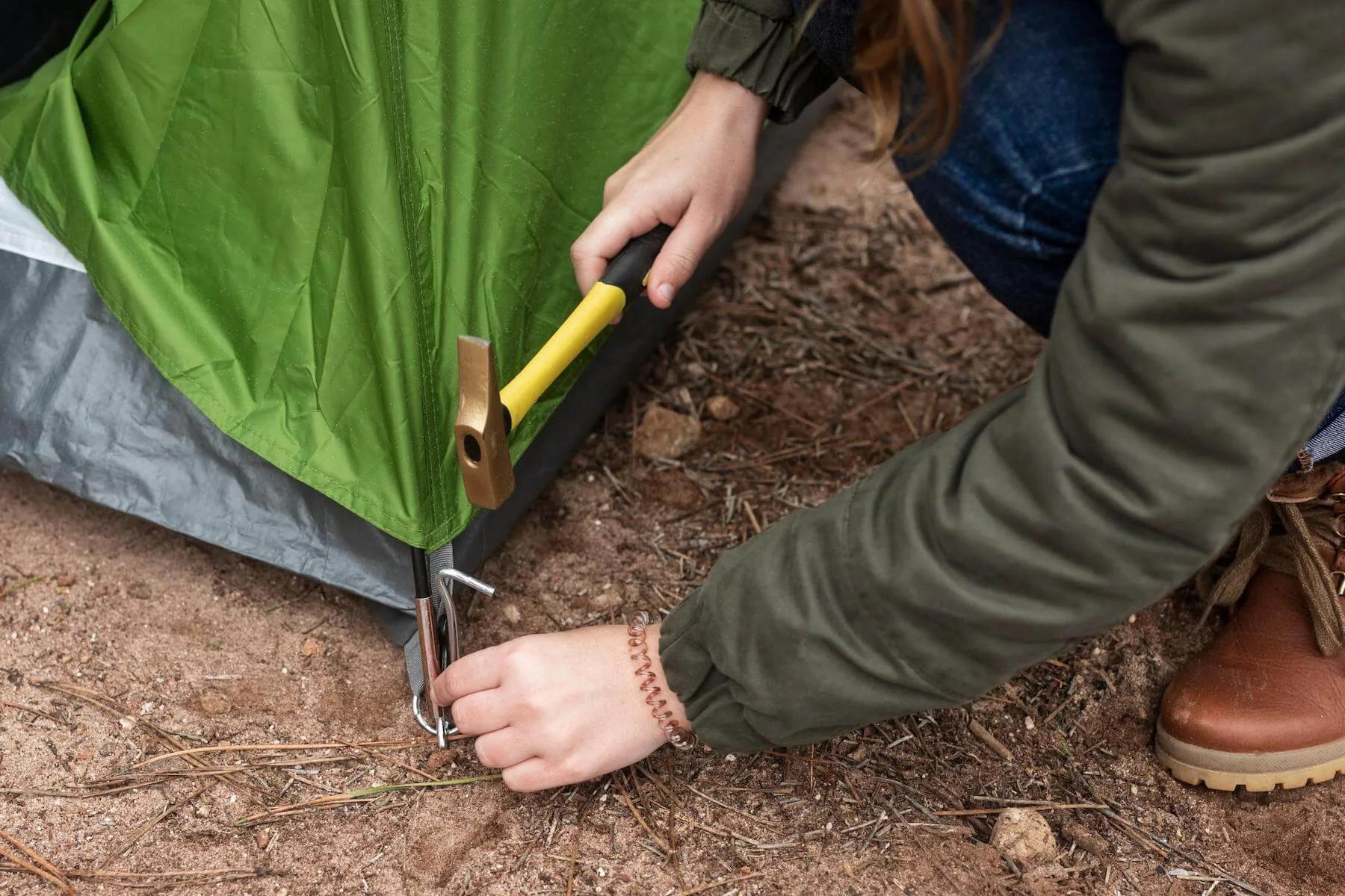 A steel tent peg being hammered into the ground.